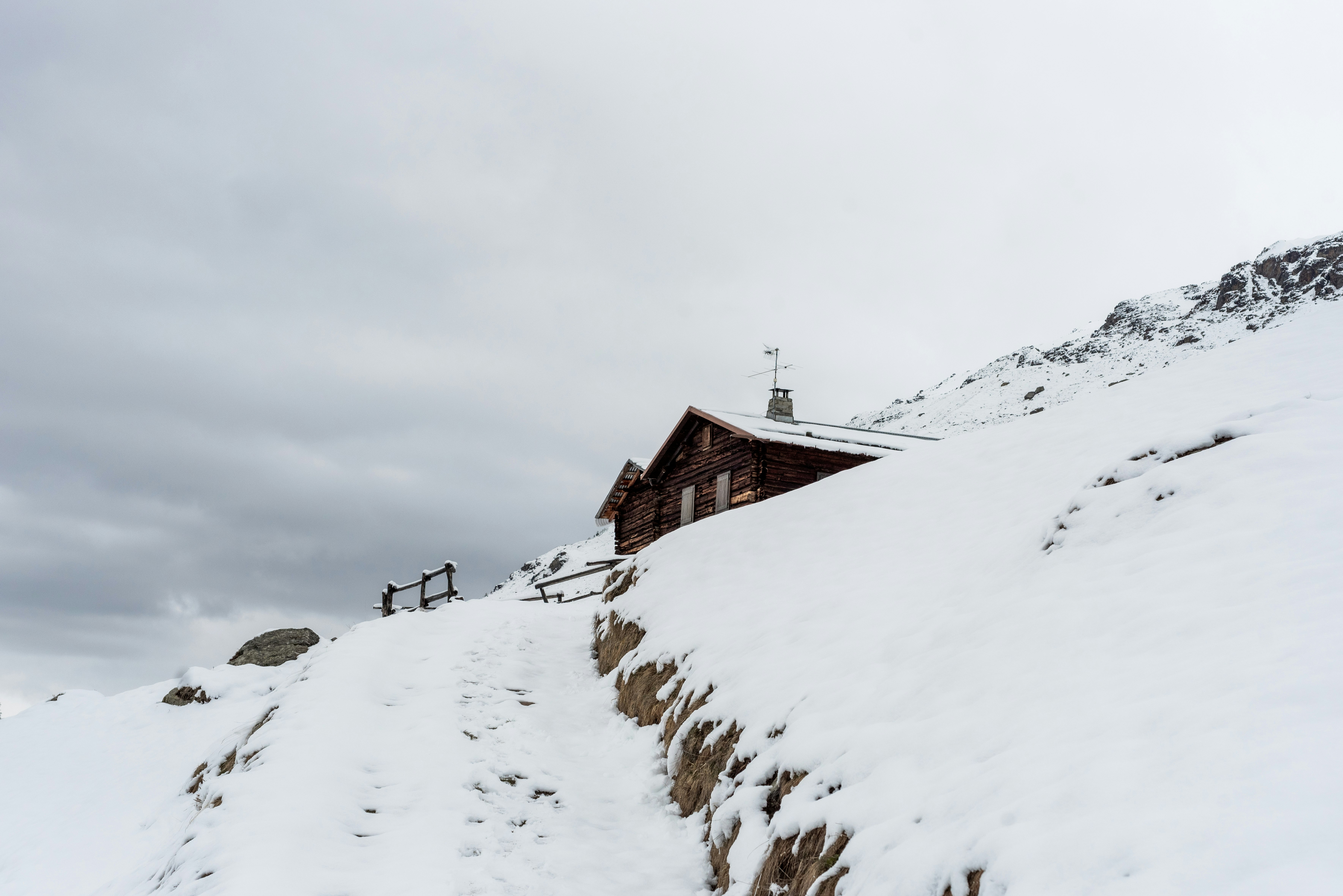 brown wooden house on snow covered ground under gray sky